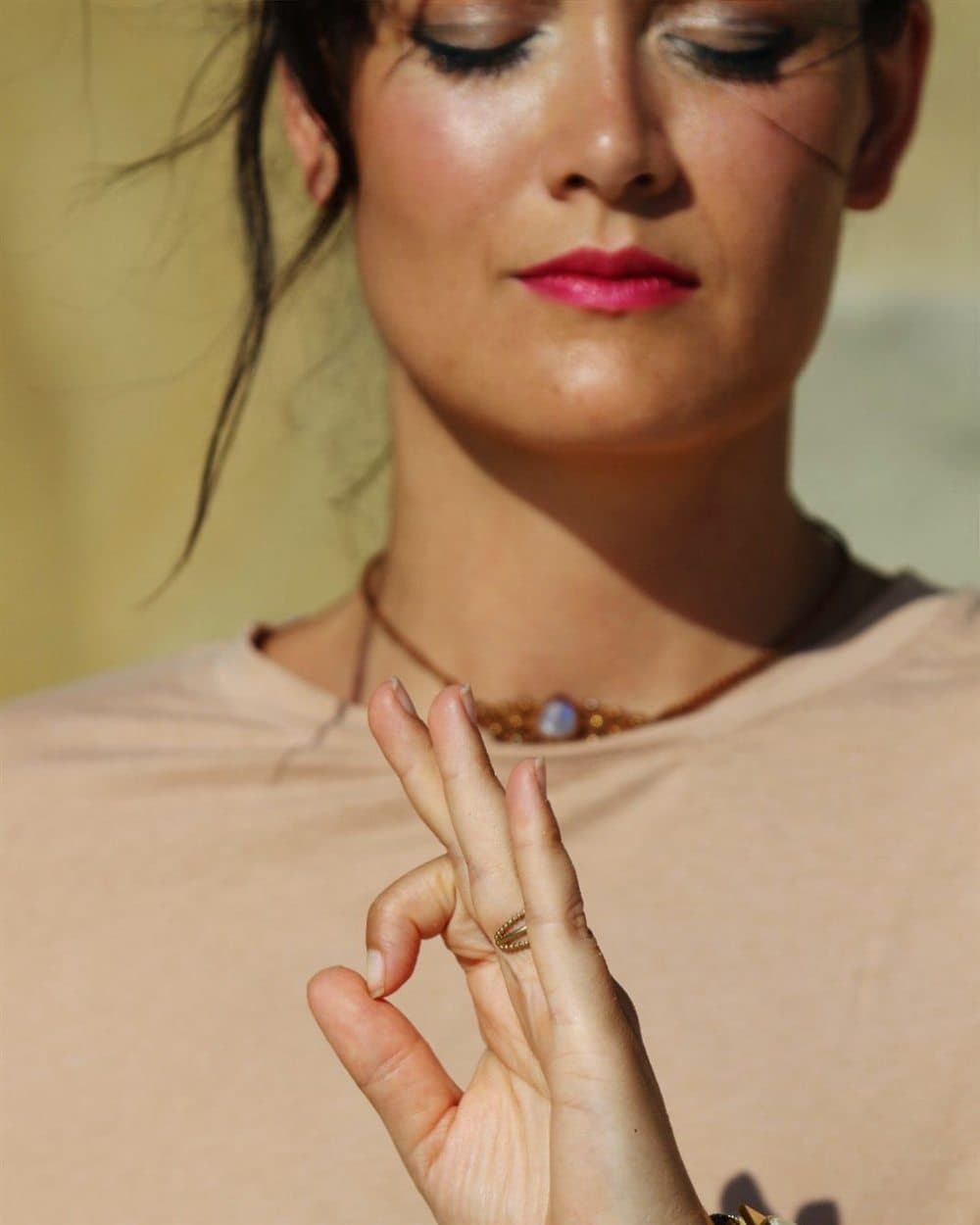 Geraldine (Gigi), eyes closed, holding a mudra hand gesture.