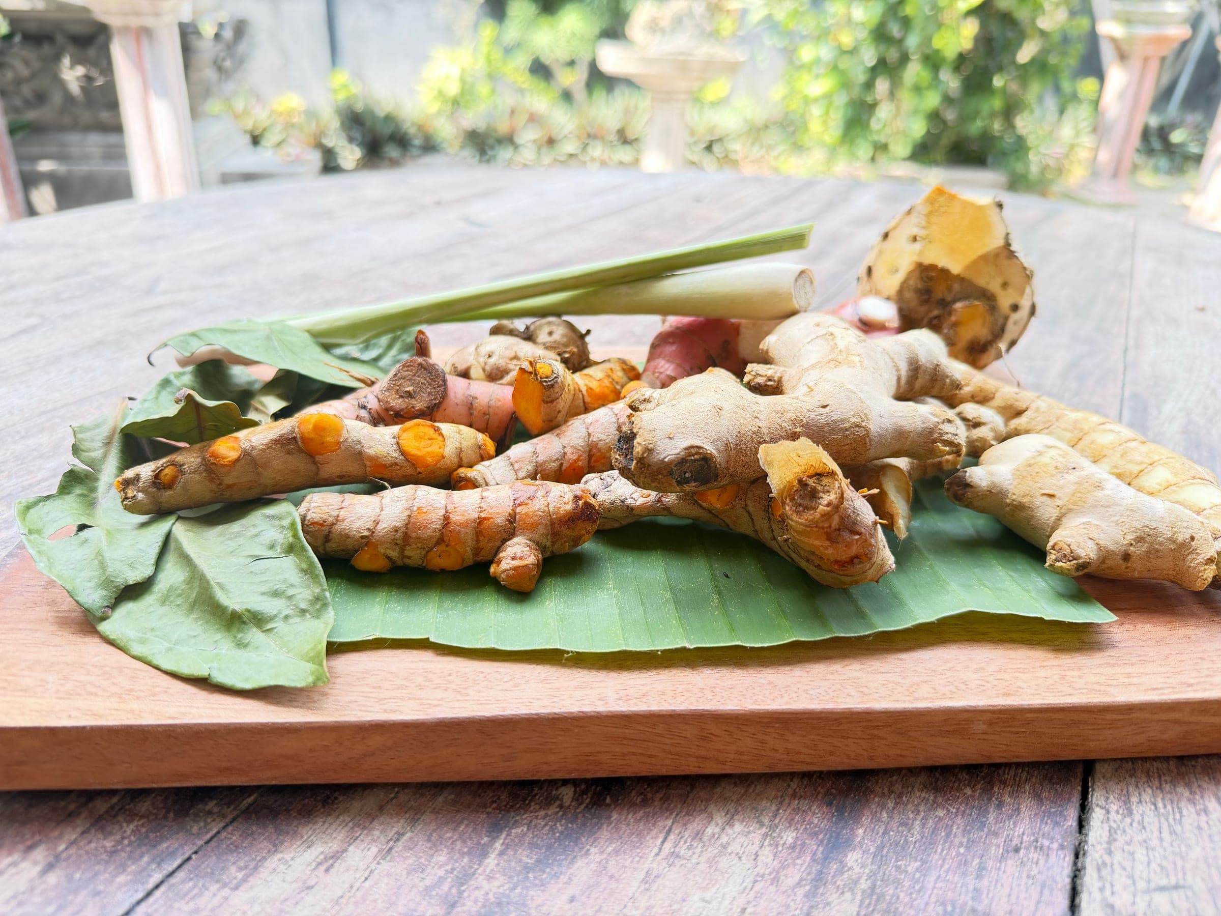Fresh ginger, turmeric and galangal roots with lemongrass on a wooden board at the Healing Home in North Bali.