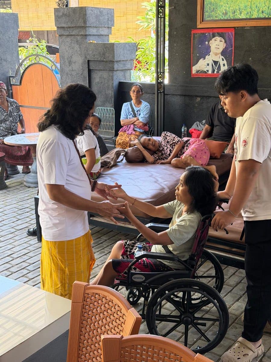 JRO reading a seated client’s condition by touch, in the open space where clients gather in the morning.