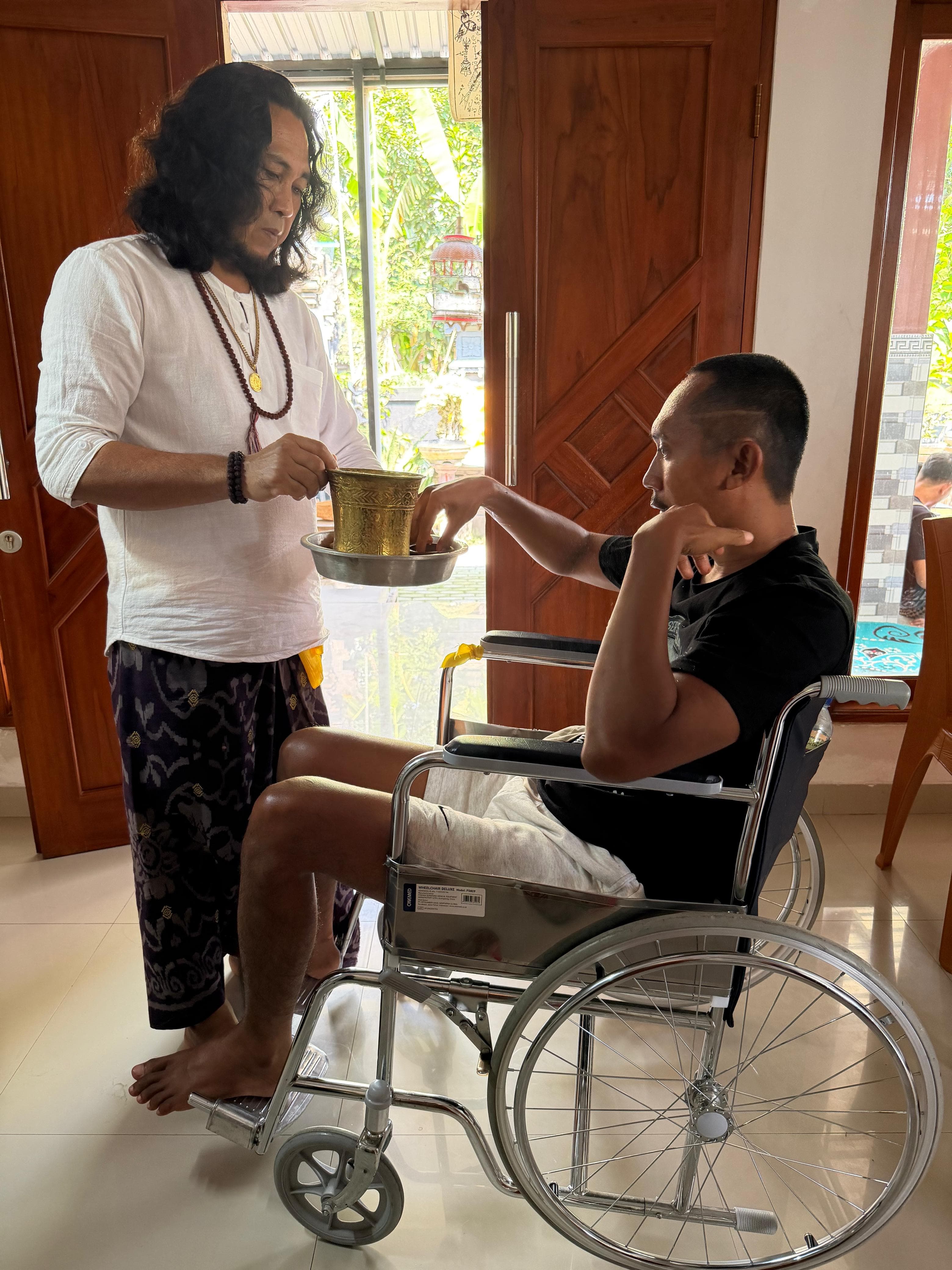 JRO offering holy water to a client in a wheelchair at the end of a treatment.