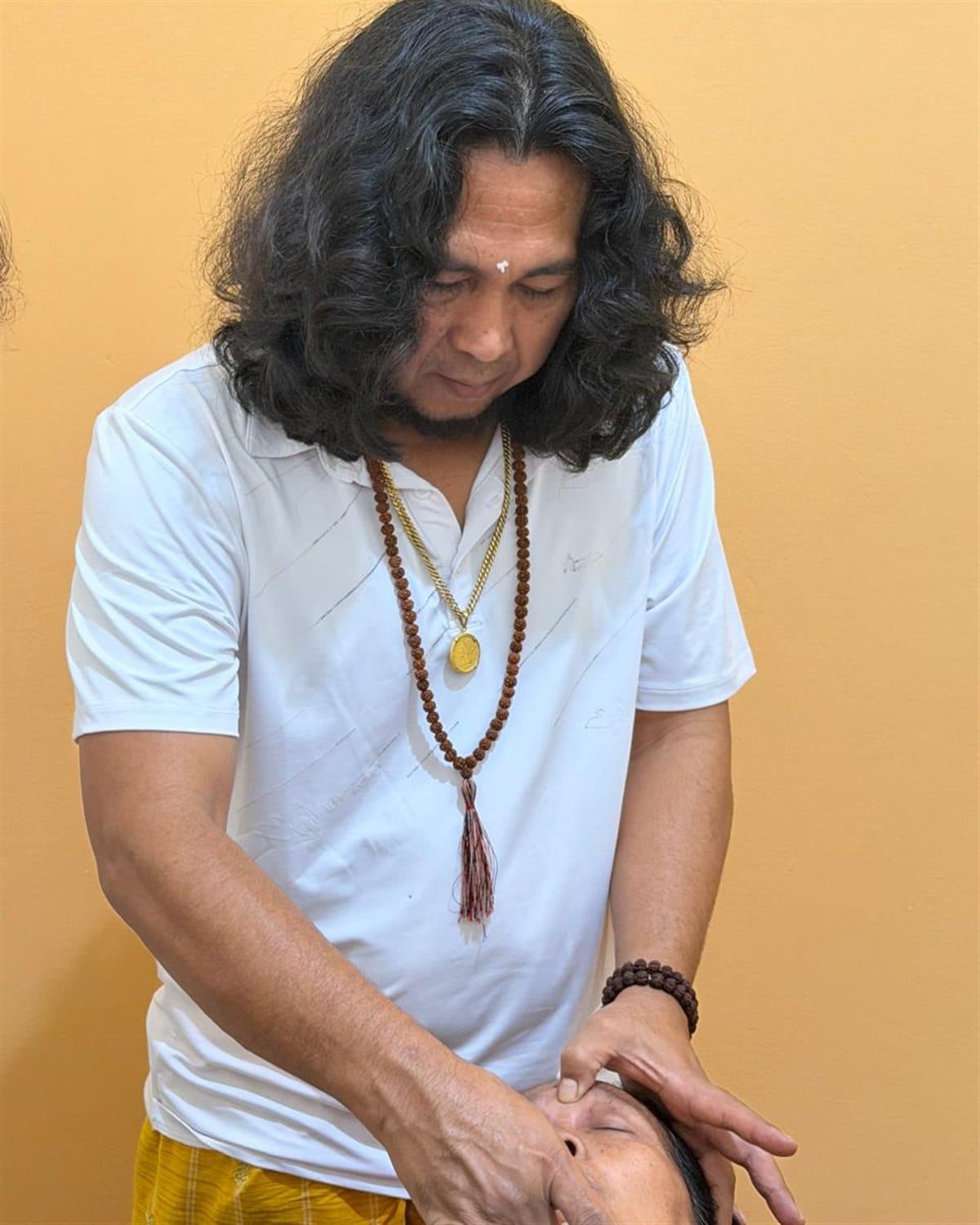 JRO bending over a client, working with both hands on their head during an individual treatment.